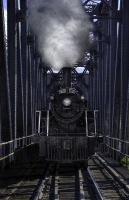 Smoke rising from a stack on a steam train on a bridge